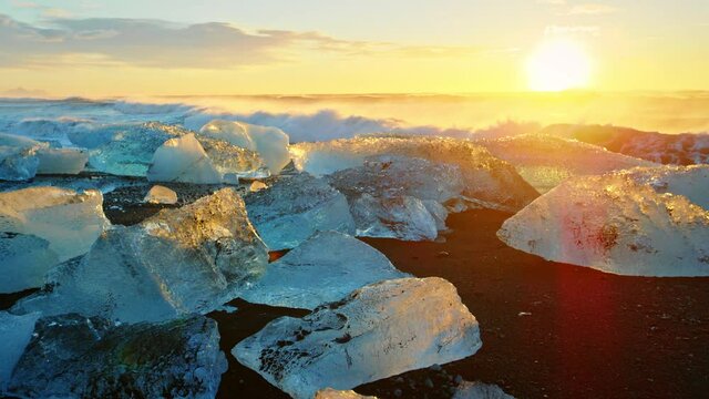 Chunks of ice on Iceland beach at sunset, close up slow motion