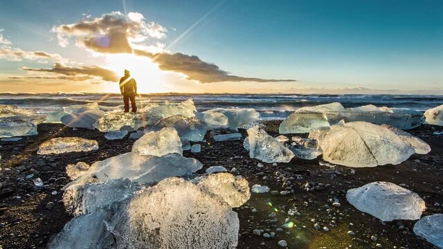 Timelapse, man admires sunset on Okulsarlon Beach in Iceland