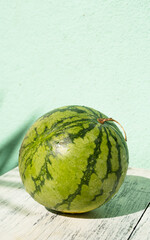 Arbuz, zielony owoc na jasnym tle, w dziennym świetle.