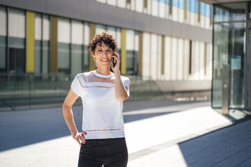 Portrait of confident mature female entrepreneur talking on mobile phone outside office