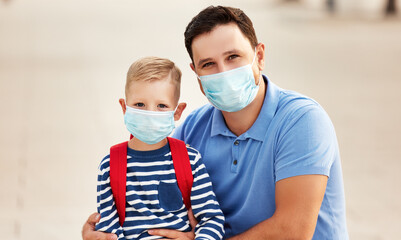 Happy father and schoolkid in protective masks.