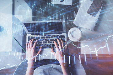 Double exposure of woman hands working on computer and forex chart hologram drawing. Top View. Financial analysis concept.