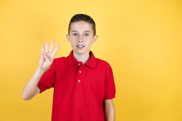 Young beautiful child boy over isolated yellow background showing and pointing up with fingers number four while smiling confident and happy