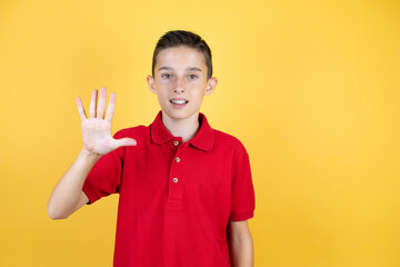 Young beautiful child boy over isolated yellow background showing and pointing up with fingers number five while smiling confident and happy