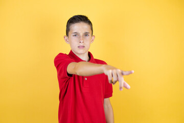 Young beautiful child boy over isolated yellow background pointing with finger surprised ahead, open mouth amazed expression, something on the front