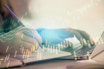 Double exposure of businesswoman hands typing on computer and forex chart hologram drawing. Financial analysis concept.