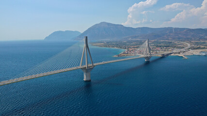Obraz premium Aerial drone photo of world famous cable suspension bridge of Rio - Antirio Harilaos Trikoupis, crossing Corinthian Gulf, mainland Greece to Peloponnese, Patras