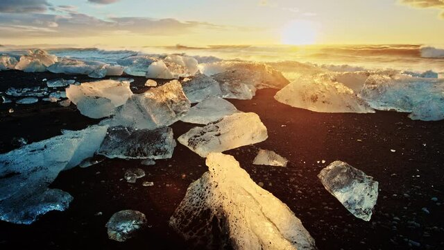 Slow motion close up, icebergs on black sand beach in Iceland at sunset