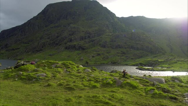 Panning aerial, woman hikes through Ireland landscape