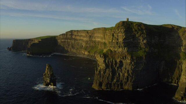 Panning aerial, sunset over castle ruins on Ireland coastline