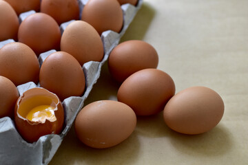 Brown eggs in carton box. Broken egg with yolk, Easter eggs In Paper Container, selective focus points.