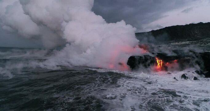Pan right aerial, waves crash over lava in slow motion