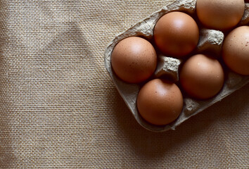Fresh chicken eggs are placed in a paper tray placed on a sack cloth.