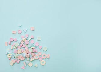 Small multicolored candies on soft blue background are scattered. Sweets, unhealthy food, love...