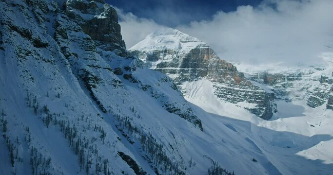 Flying over snowy mountainside in Banff National Park, helicopter pov