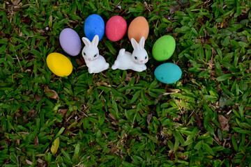 Fototapeta na wymiar Easter bunny and Easter eggs, rabbit statues and colorful eggs in the garden.