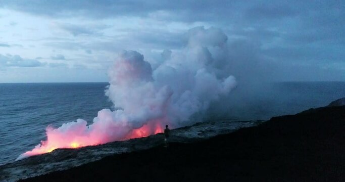 Pan right aerial, steam from lava along coastline at dusk