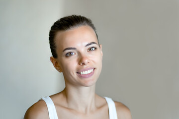 A young brunette girl looks into the camera and smiles, her head tilted to the left. close up