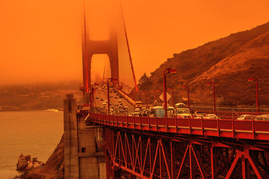 Cars crossing Golden Gate Bridge from Lime point. Smoky orange sky the bridge of San Francisco city for California fires in September 2020 in America. Wildfires composition.