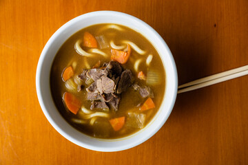 Asian food. soup with noodles, meat and pumpkin. Chinese sticks.