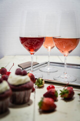 Three wines in a glass with fruit on a white table.
