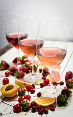 Three wines in a glass with fruit on a white table.