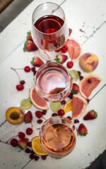 Three wines in a glass with fruit on a white table.