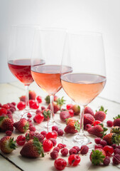 Three wines in a glass with fruit on a white table.