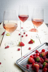 Three wines in a glass with fruit on a white table.