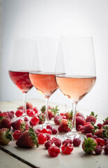 Three wines in a glass with fruit on a white table.