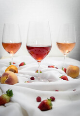 Three wines in a glass with fruit on a white table.