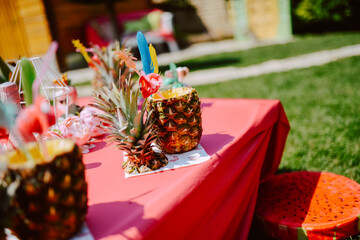 Naklejka na ściany i meble Decorated table with pineapple cocktails to celebrate a bachelorette party in a beautiful garden. The girls are having a party
