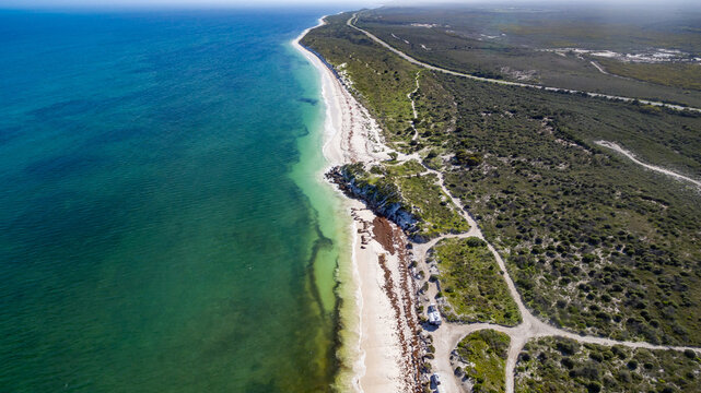 High Level Landscape Aerial View Of 4WD And Modern Caravan Parked Adjacent To A Sparkling Sunny Beach.
