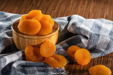 Dried apricots in bowl on fabric