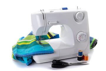 a white electric sewing machine sewing a seam with scissors and spools of thread isolated on white