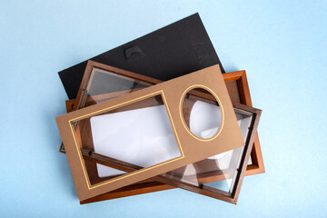 top down view of an empty wooden photo frame and mat with another frame open on a blue table