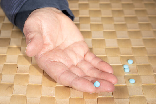 closeup as an elderly male holds a generic pill from an 81 milligram ASA ( aceta cyclc acid) pill to treat a heart condiotion