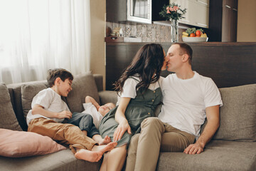 Obraz premium A family with two children is sitting on the sofa. Weekend at home. Spending time together