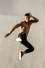 Handsome shirtless caucasian sportsman doing jump kick in mid air outdoors