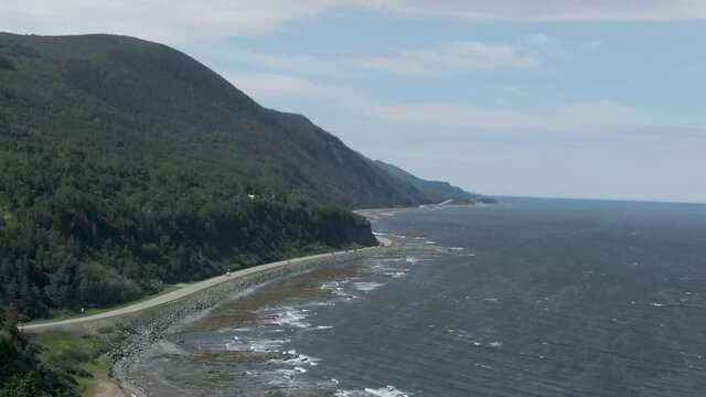 Cars Driving And Travelling The Winding Road Of Saint Anne des Mont By The Saint Lawrence River At Daytime In Quebec, Canada. - aerial drone shot