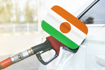 Flag of Niger on the car's fuel filler flap with gas pump nozzle in the tank.