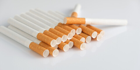 Cigarettes with a yellow filter lie on a white surface
