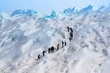 grupo de personas en fila subiendo por el hielo hacia la cima del glaciar Perito Moreno, en la patagonia Argentina