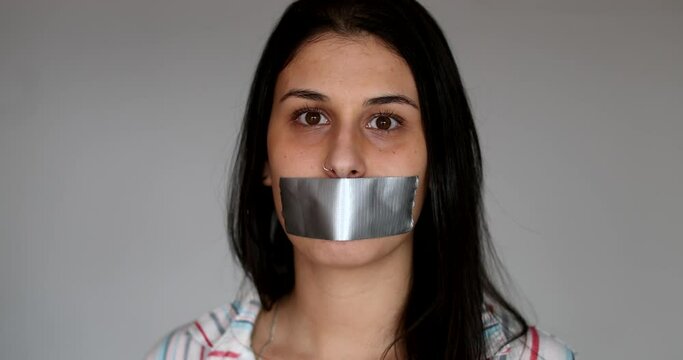 Silenced young woman having her voice shut mouth taped