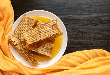 Honeycombs in white plate on the wooden table. Natural organic bee product. Healthy lifestyle. Copy space for your text. Close-up photo.