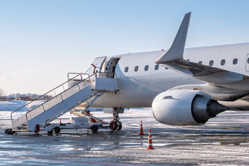 White airliner with passenger boarding stairs at the cold winter airport apron