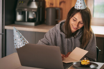 Happy cheerful young woman with smile rejoicing writes a greeting card at home at the table. Birthday or anniversary concept © kucherav