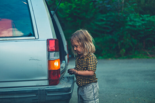 Preschooler getting something from the trunk of a car