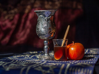 Rosh Hashana still life with apple, honey and kiddush cup using shallow depth of field and selective focus