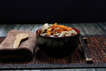 Traditional fried and stirred sliced pork meat with teriyaki sauce and serving with kimchi (Korean mixed pickled vegetable) topping on cooked rice. Famous street food set menu in Asia restaurant. 